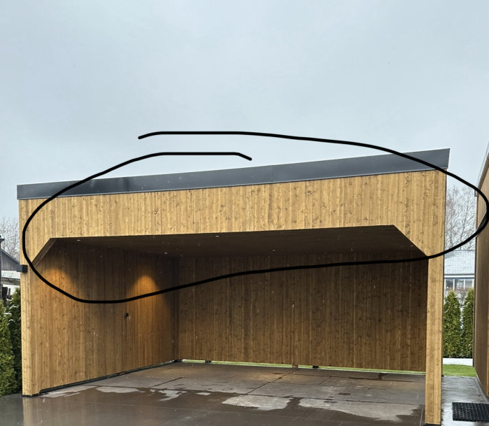 Modernt, träbeklätt byggnadsverk med platt tak, öppen sida och något ritat ovanpå i svart.