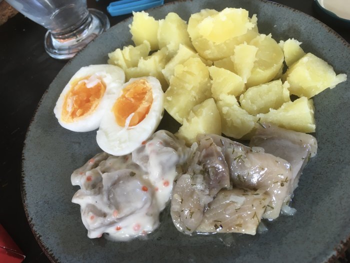 Tallrik med potatis, kokta ägg och sill i gräddig sås. Enkelt, traditionellt, svenskt midsommar eller påskbord.