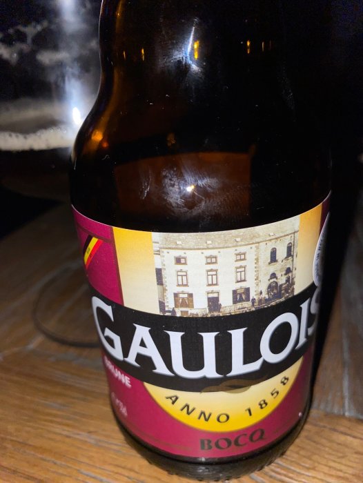 Ölflaska med etikett 'GAULOISE', Anno 1858, BOBQ, närbild, mörk bakgrund, reflektioner.