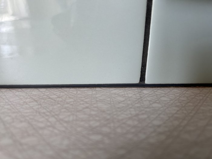 Närbild av kakel och fog på ett köksbord, naturligt ljus, skarpa linjer, minimalistisk.