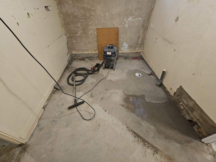 Renoveringsprojekt pågår, tomt rum, avgrävning i golv, verktyg och material synliga, oavslutad konstruktion.