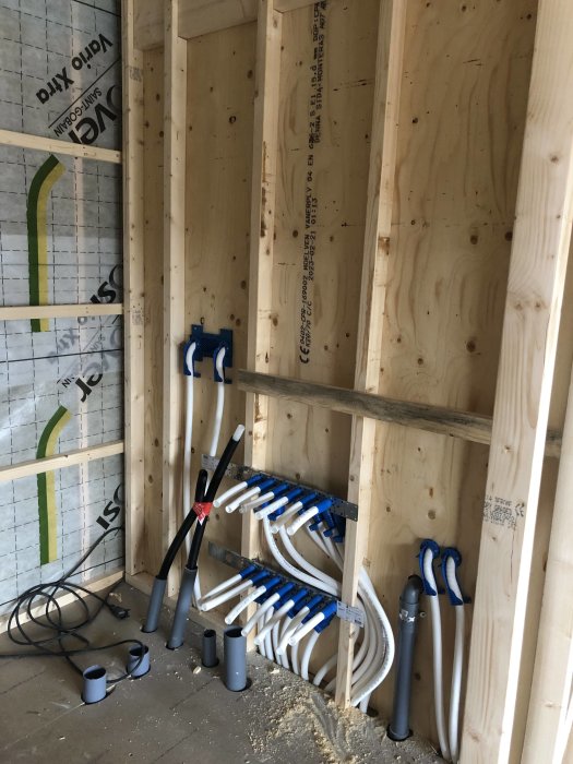 Installation av VVS i träregelverk under konstruktion med isolering och synliga plaströr.