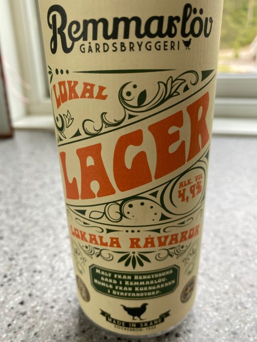 En ölflaska med etikett "Remmarlöv Gårdsbryggeri, lokal lager, alkoholvolym 4,7%, made in Skåne".
