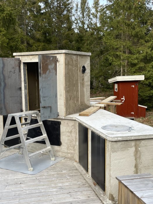 Renovering pågår, träkonstruktion, stege, ventil, uthus, omgivet av skog i dagsljus.