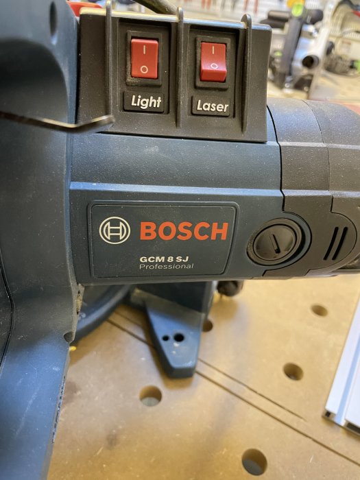 Bosch professionellt verktyg, ljus- och laserknappar, arbetsmiljö i bakgrunden, verktygsdetalj, fokus på märkeslabel.