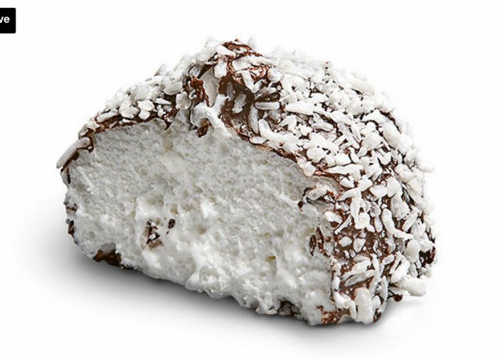 En halv kokostopp med chokladtäcke isolerad på vit bakgrund. Luftig småkaka med riven kokos, traditionellt bakverk.