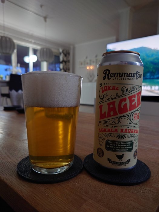 Ölglas på bord intill en burk lager nära TV. Interiör hemmiljö.