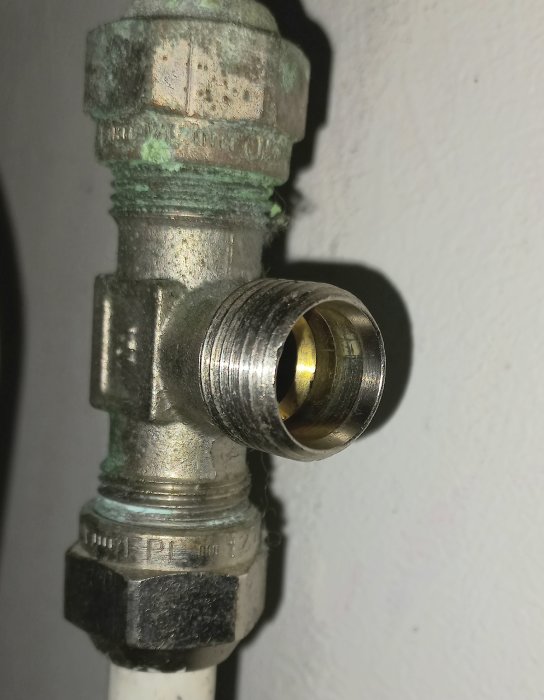 Vattenledningskran med korrosion och en öppen kopplingsdel, monterad på vägg.