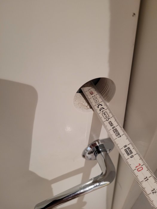 Mätverktyg bredvid en vägg, mätning av ett cirkelformat objekts diameter, inomhus, närbild.