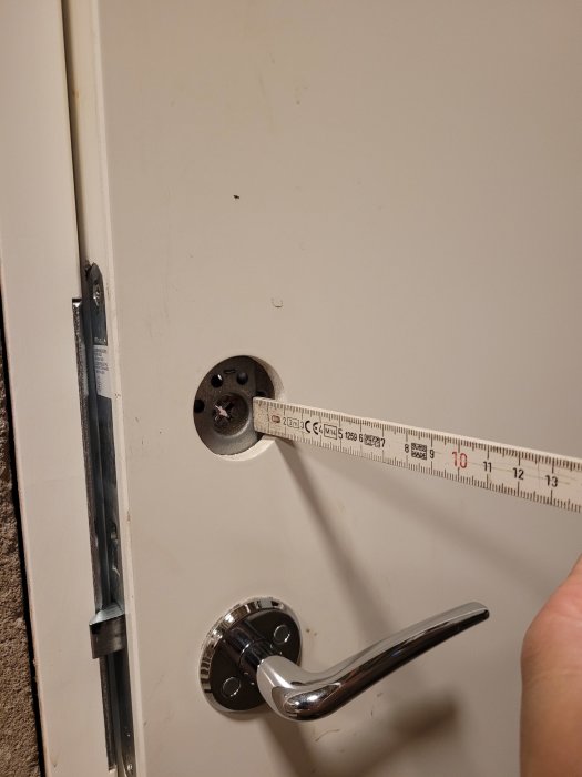 Mätning av avståndet mellan dörrkarm och dörrhandtag med en hopfällbar tumstock.