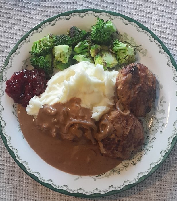 Köttbullar, potatismos, brunsås, lingonsylt, stekt broccoli. Tradionell svensk måltid på dekorativt porslin.