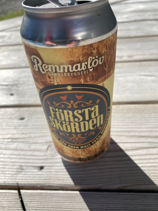 Ölburk på träyta i solljus, text "Remmarlöv Gårdsbryggeri", "Första Skörden".