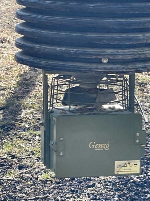 Grönt Genzo elektroniskt skåp under spiralformad struktur ute i naturen.