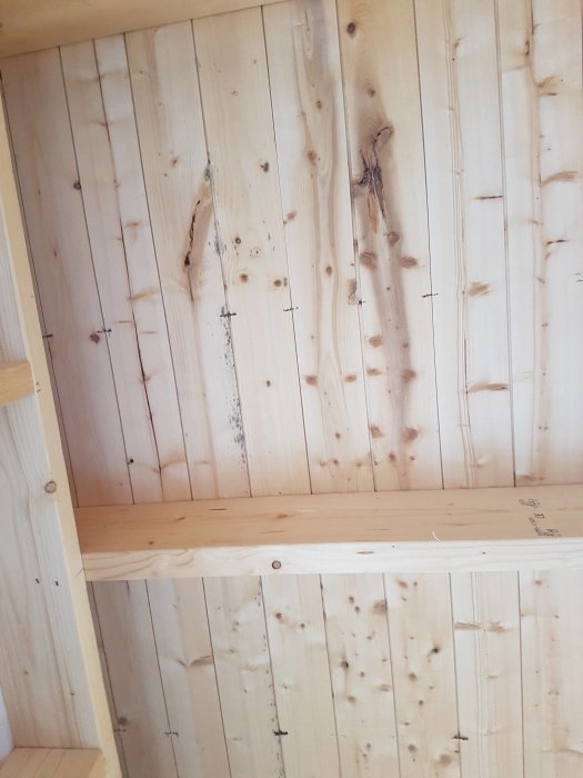 Inredning av trä, hyllplan, knutar och skruvar, ljus, naturlig textur, vertikal orientering.