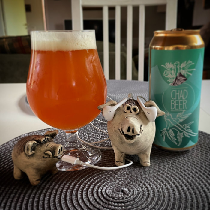 Ölglas med skum, ölburk, figuriner av grisar med hörlurar, inomhusscen.