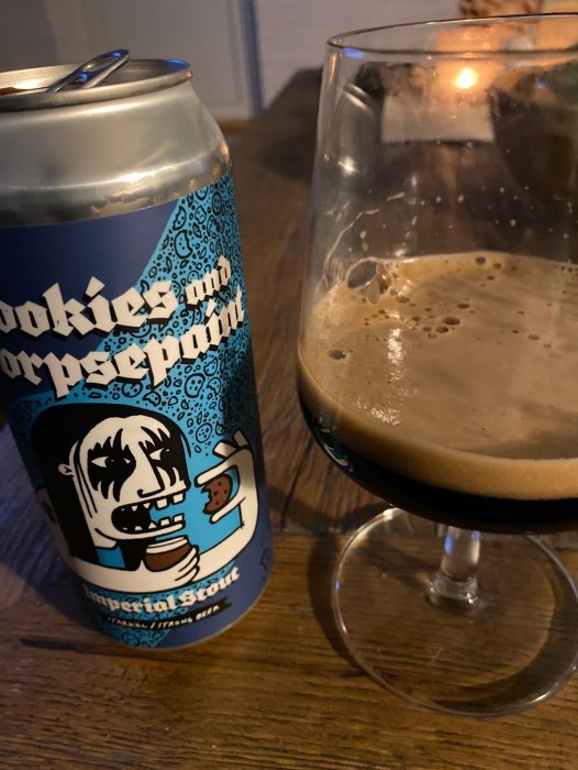 Öppnad ölburk och ett glas med mörkt skummande öl, konstnärlig etikett. Möjligtvis en ölprovning.