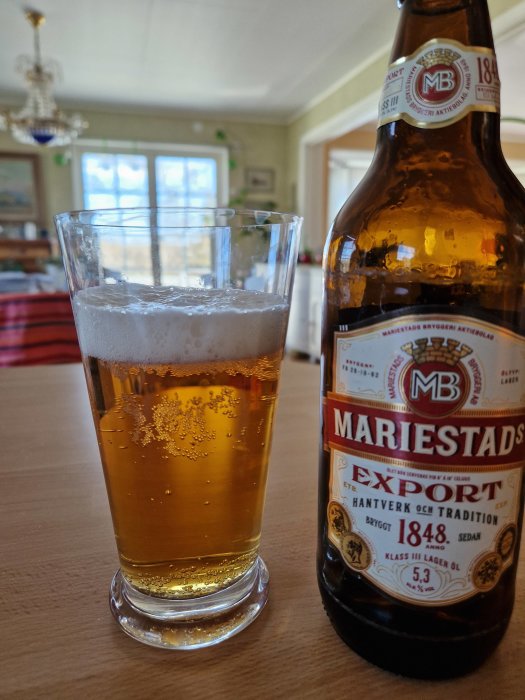 Ölglas delvis fyllt, Mariestads Export flaska, inomhus, köksbakgrund.