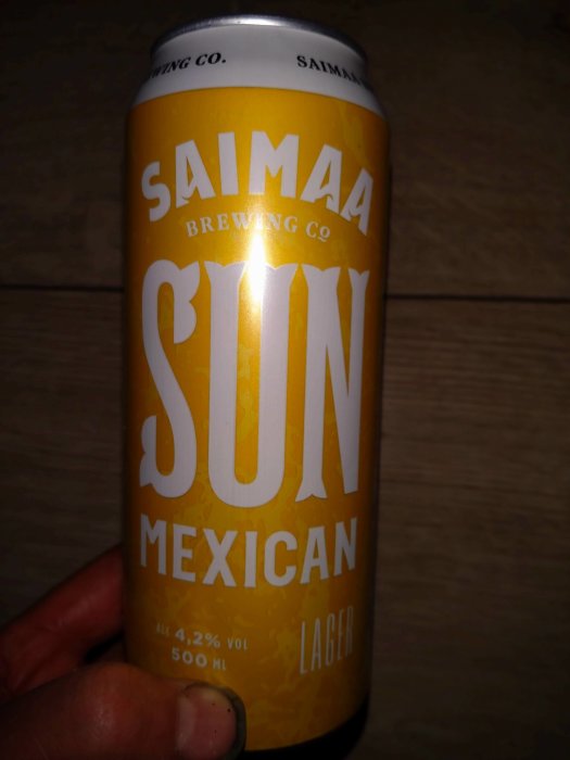 En hand håller en ölburk märkt "Saimaa Brewing Co., SUN MEXICAN LAGER," alkoholhalt 4,2%, 500 ml.