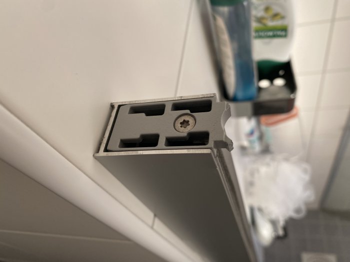 Väggmonterad hållare för rakhyvlar, toalettartiklar i bakgrunden, badrumsinteriör, suddig förgrund.