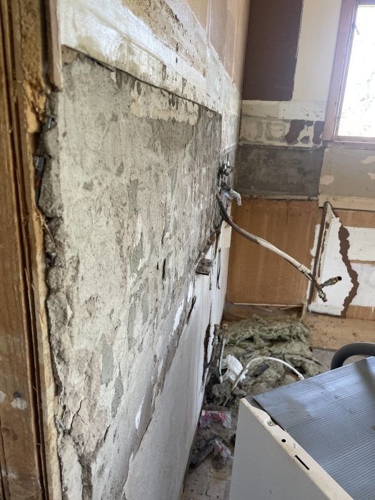 Förstörd inomhusmiljö, exponerade väggar, nedrivet gips, byggavfall, trasig struktur, renoveringsbehov, förstörelse, orenoverat rum.