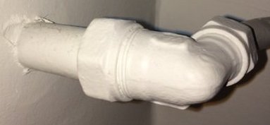 Ett vitt rör med isolering eller tätning på vägg, ser ut reparerat eller skyddat.