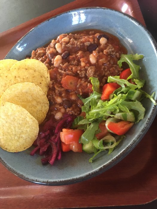 Chili con carne med bönor, tacoskal, sallad, rödbetor på blå tallrik, maträtt, färgrik, hemlagad måltid.