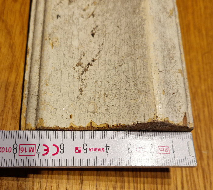 Ett gammalt, slitet bokband med måttband, tjocklek mäts, på ett träbord.