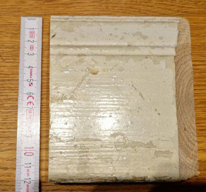 Ett block av okänt material bredvid en linjal på träunderlag.