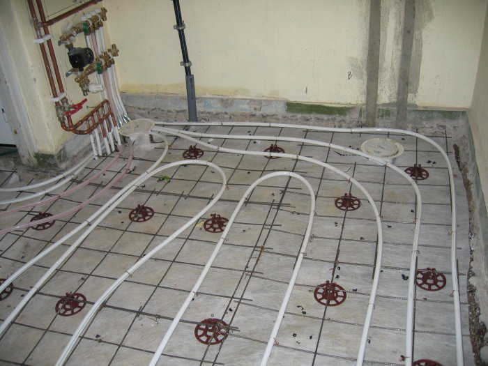 Installation av golvvärme, rör och fixeringsanordningar på isolerad underlag, vid taget i en byggnadsprocess.