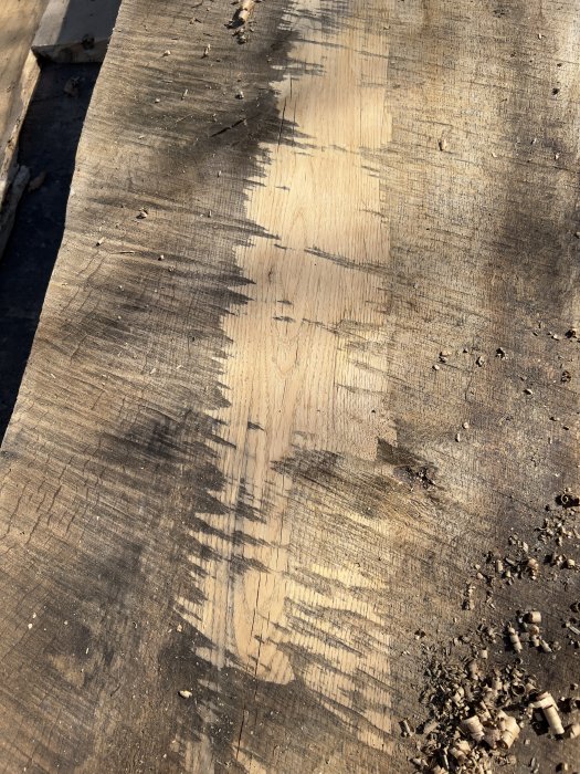 Gamla träplankor med sågspån och skuggor. Slitna och möjligen del av ett byggarbetsområde.