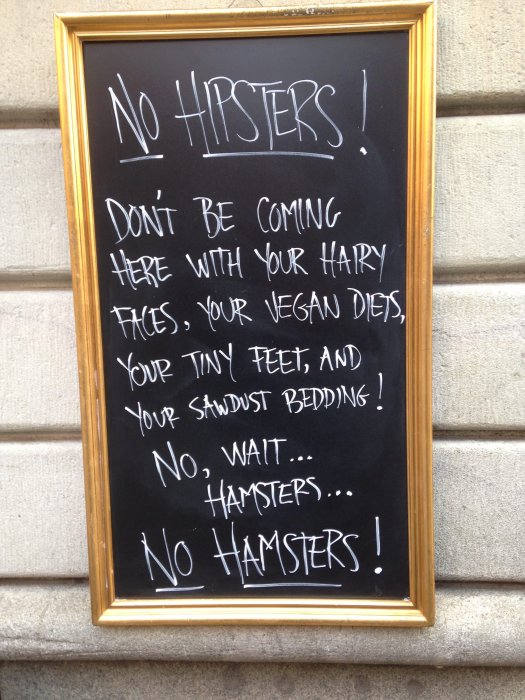 Svart tavla med humoristisk text som rättar "No Hipsters" till "No Hamsters."