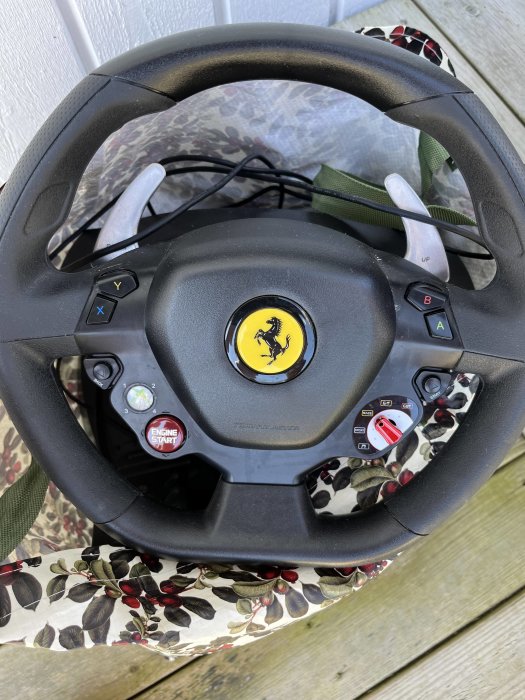 Ferrariratt med knappar och växelpaddlar, mot bakgrund av blommigt tyg.