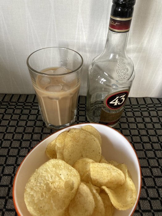 Ett glas med iskaffe, tom Likör 43-flaska och en skål potatischips.