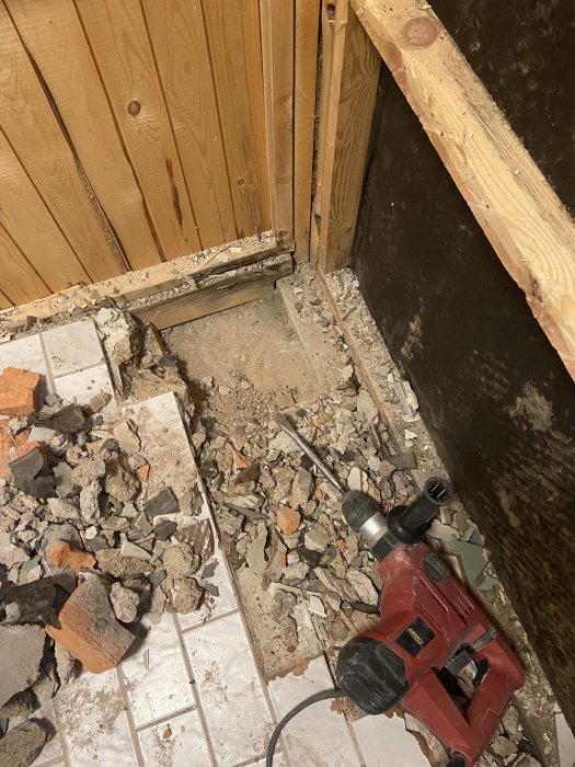 Renovering pågår, rörmokarverktyg, trasigt kakel och tegel, dammigt byggavfall, träpanel, exponerad konstruktion.