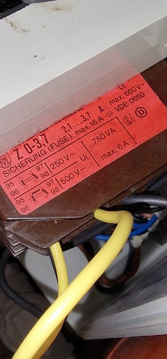 En säkring med tekniska specifikationer och elektriska kablar i förgrunden. Industriell, teknisk komponent.
