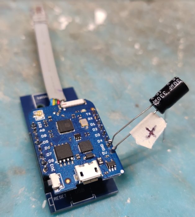 Arduino-kort med lödda komponenter och kabelkoppling, kondensator med tapetejpad flagga, elektronikprojekt eller reparation.
