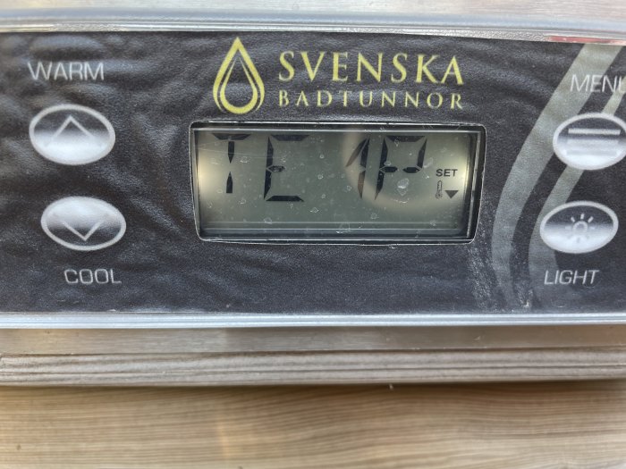 Digital kontrollpanel för badtunna, visar 40 grader Celsius, knappar för uppvärmning, kylning, inställningar och belysning.