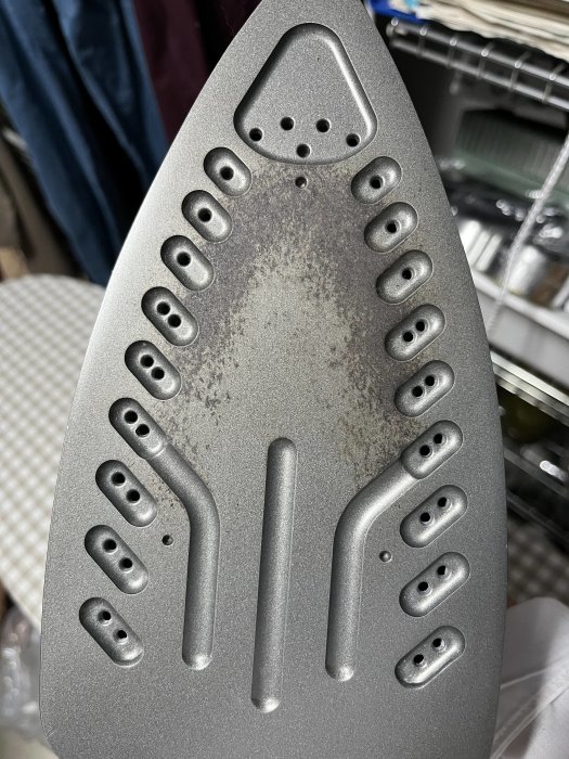 Strykjärnsplatta, grå, smutsig, många hål, förångningsöppningar, slitage, metallisk yta, närbild, ingen bakgrundsinformation.