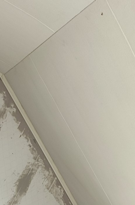 Hörn av ett rum med smutsigt tak och skadad vägg, behöver renovering.