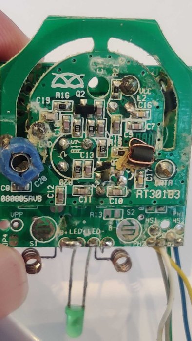 Grönt kretskort med resistorer, kondensatorer, anslutningstrådar, och en spole. Används i elektronisk apparat.