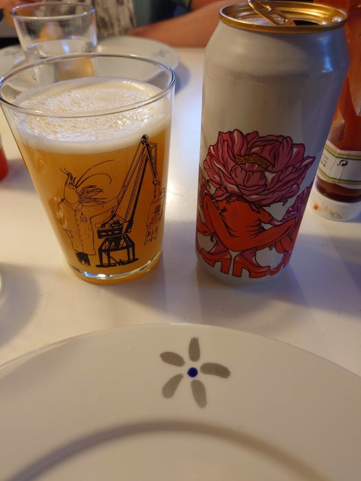 Öl i grafiskt dekorerat glas och burk, tom tallrik med blomdekor, inomhus, måltidssituation, avslappnad atmosfär.