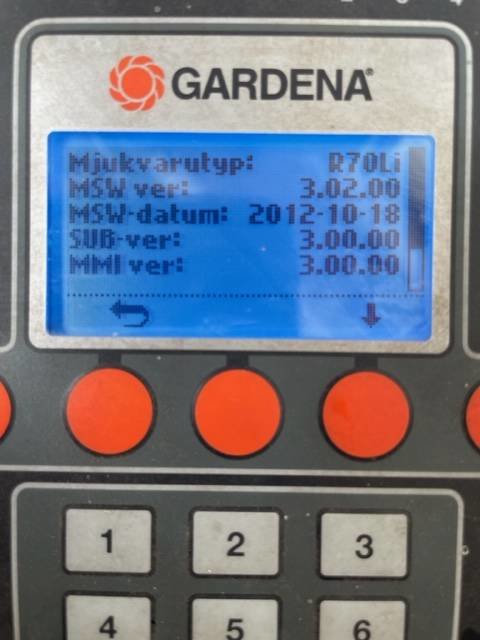 Digital display på en Gardena-enhet med knappar, visar versioner av programvara och datum.
