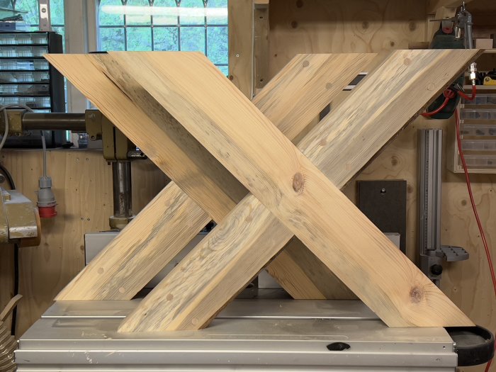 Träben på arbetsbänk formar ett "X", snickeriverkstad, verktyg i bakgrunden.