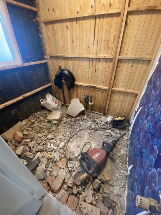 Renoveringsarbete med röran av rivna tegelstenar, verktyg på golv, träväggar, avslappnad miljö.