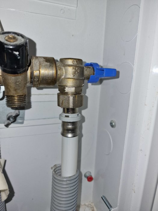 VVS-installation, vattenrör med avstängningsventil och flexibel anslutningsslang nära vit vägg.