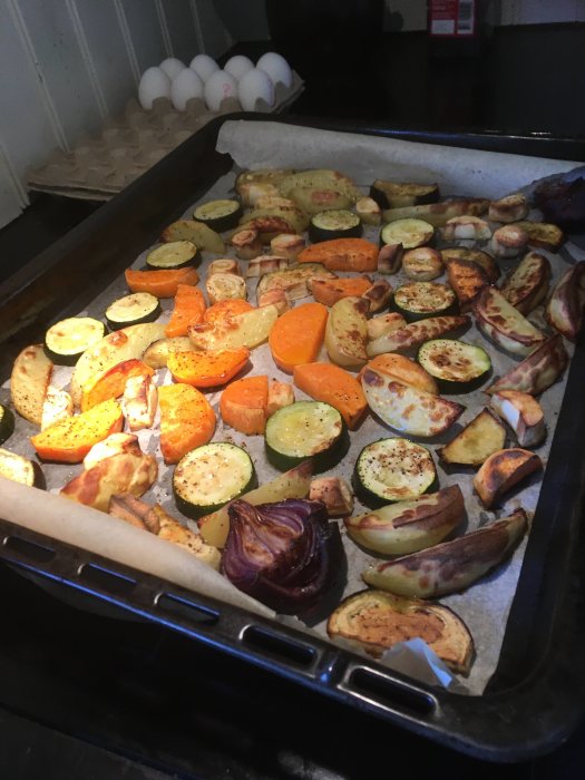 Ugnsbakade grönsaker på en bakplåt, inklusive sötpotatis, zucchini, lök, och potatis.