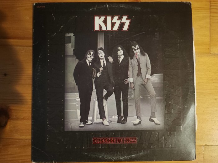 KISS skivomslag, "Dressed to Kill", fyra medlemmar i smink, stadsbakgrund, slitet exemplar.