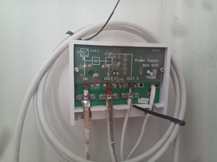Elkopplingsskåp med kablar, säkringar, märkt "Power Supply", monterat på vägg, teknisk utrustning.