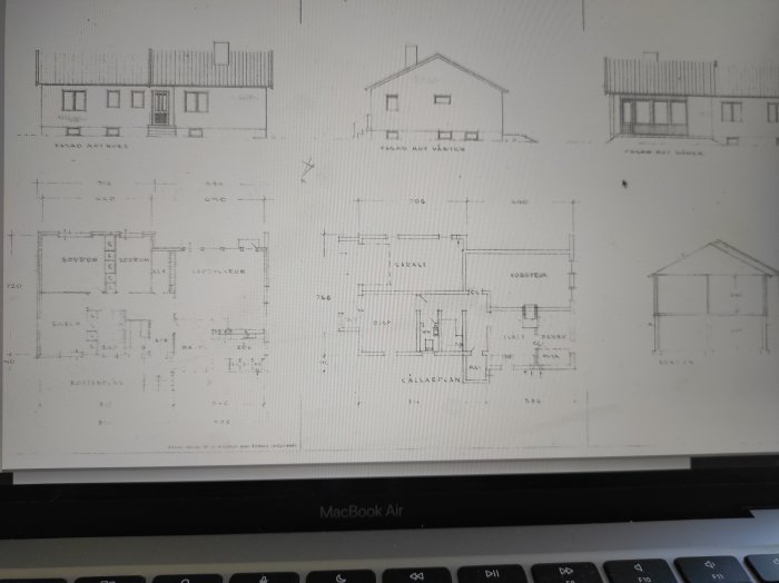 Arkitektoniska ritningar av ett hus visade på en laptop-skärm. Fasader, planlösning och sektion inkluderade.