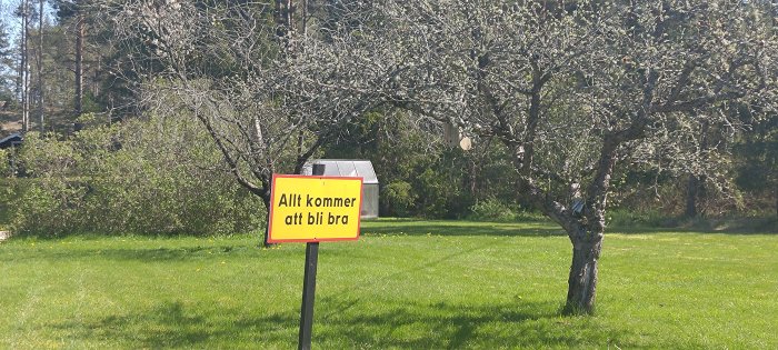 Träd, gräsmatta, soligt, skylt med texten "Allt kommer att bli bra".